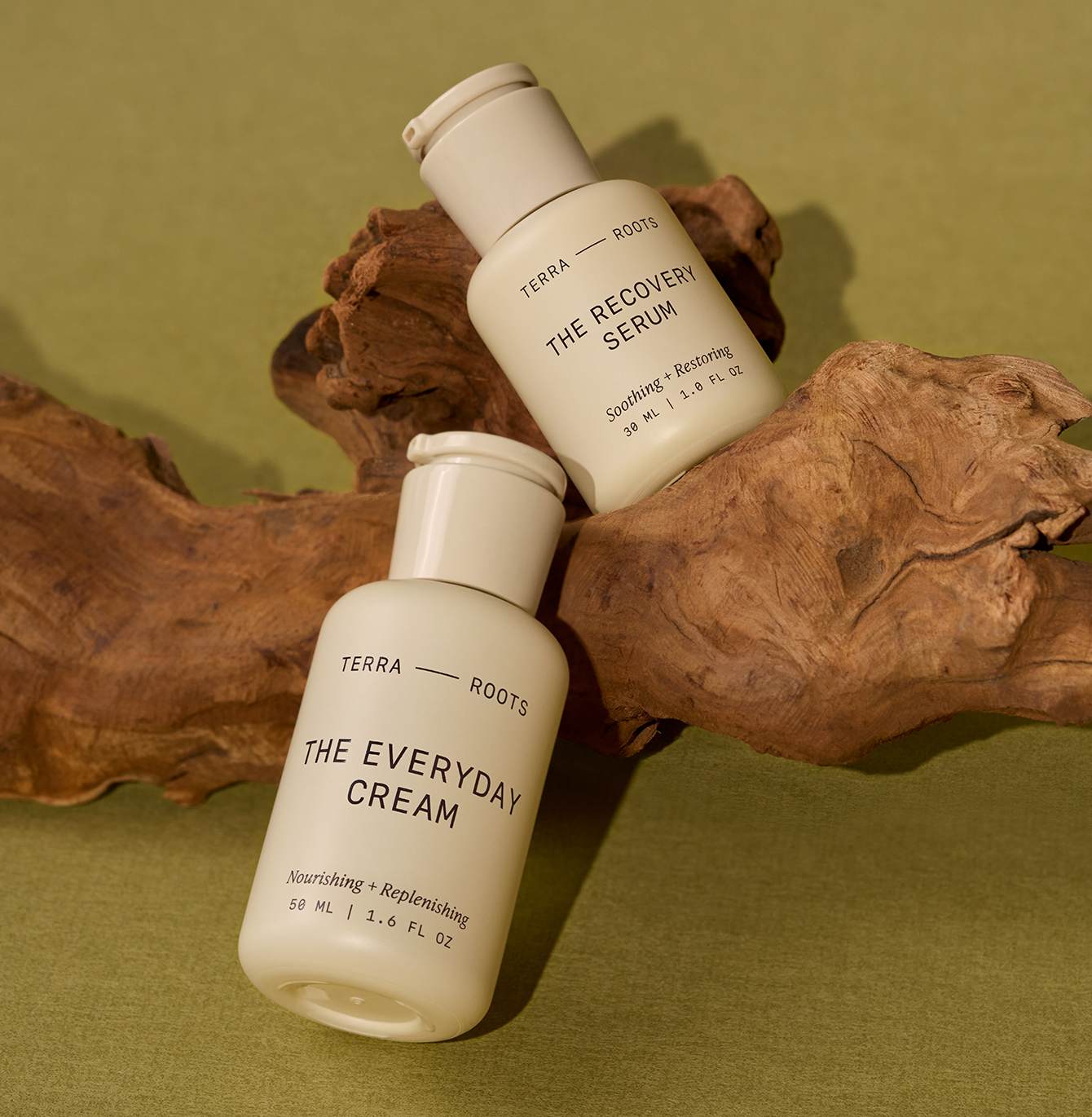 Terra Roots serum and cream bottles on a branch